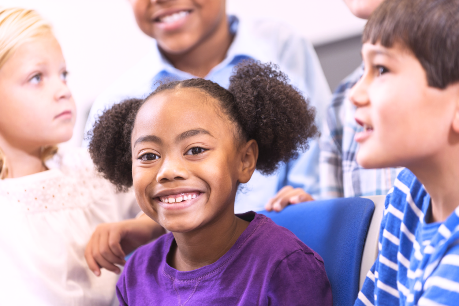 Neljä lasta, keskiössä lilapaitainen, tumma ja hymyilevä lapsi.