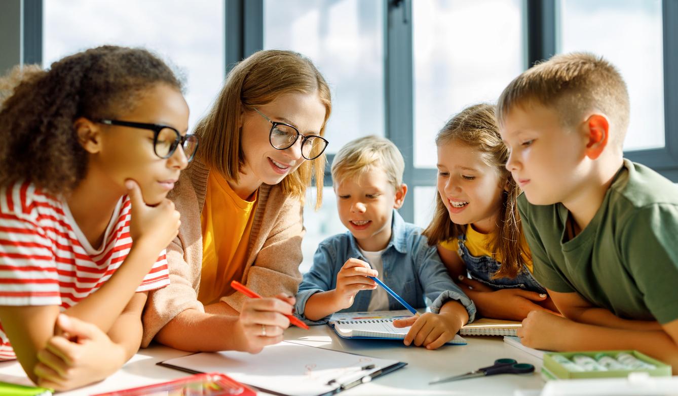 Läraren hjälper en grupp på fyra barn i skolan.