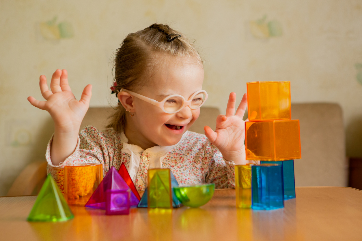 Barn med downs syndrom leker med leksaker.