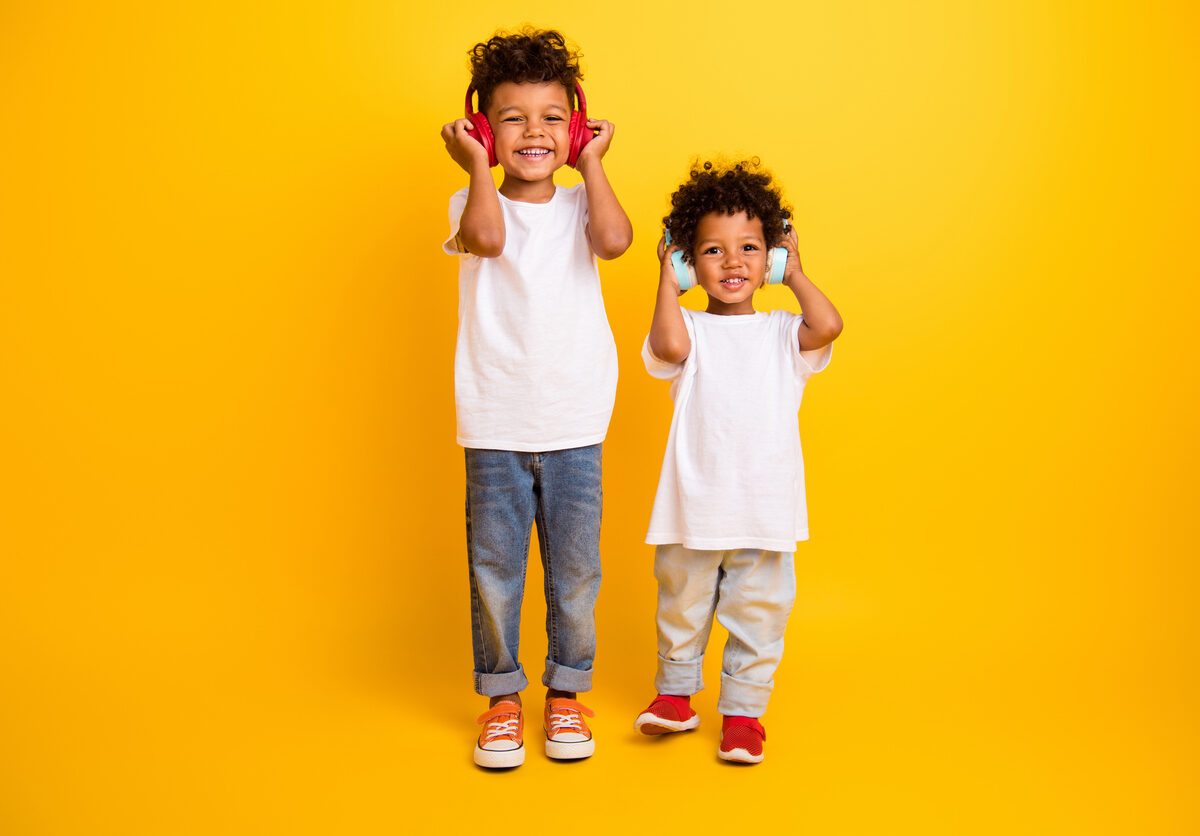 Två barn med hörlurar framför en gul bakgrund.